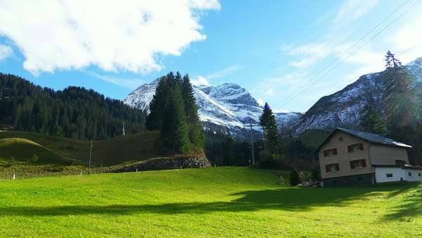 Vorbei an grünen Wiesen und Schnee bedeckten Bergen